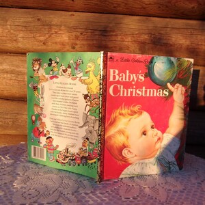 May include: A vintage Little Golden Book titled "Baby's Christmas" with a red cover featuring a baby reaching for a Christmas ornament. The book is open, revealing a green cover with cartoon characters.