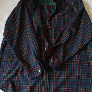 May include: A long-sleeve button-down shirt featuring a dark green, navy blue, and red plaid pattern. The shirt has a dark green inner collar lining, a buttoned front placket, and buttoned cuffs. A Pendleton brand label is visible at the neck.