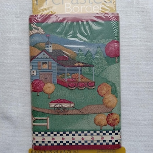 May include: Pre-pasted wallpaper border featuring a quaint farm scene with a blue building, red trees, and a wagon filled with produce. The border has a checkered pattern with red apples. The package is 6.75 inches wide.