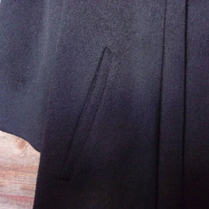 May include: A black wool cape with a single seam down the back.