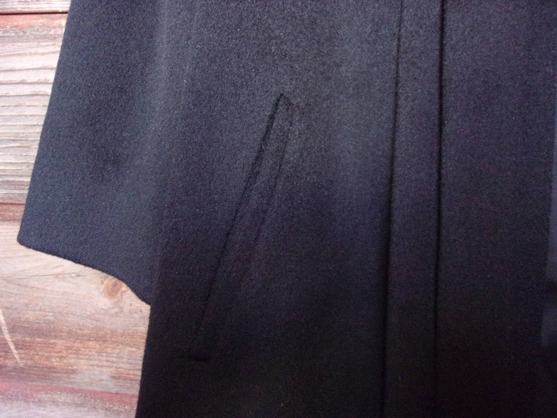 May include: A black wool cape with a single seam down the back.