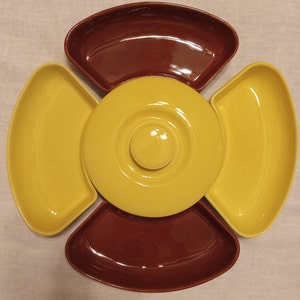 May include: A four-sectioned ceramic serving dish with a central round bowl. The outer sections are yellow and the central bowl and inner ring are yellow. The outer sections are brown on the inside.