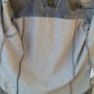 May include: A gray denim jacket with a Harley Davidson logo on the back. The jacket is unzipped and the lining is visible.