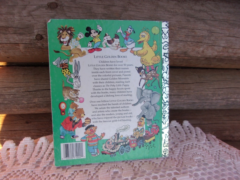 May include: Back cover of a Little Golden Book featuring illustrations of various cartoon characters, including Mickey Mouse, Donald Duck, and Big Bird. The book has a green border with text that reads "LITTLE GOLDEN BOOKS".