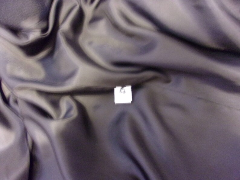 May include: A close-up of a dark gray fabric with a white tag that says "L" on it.