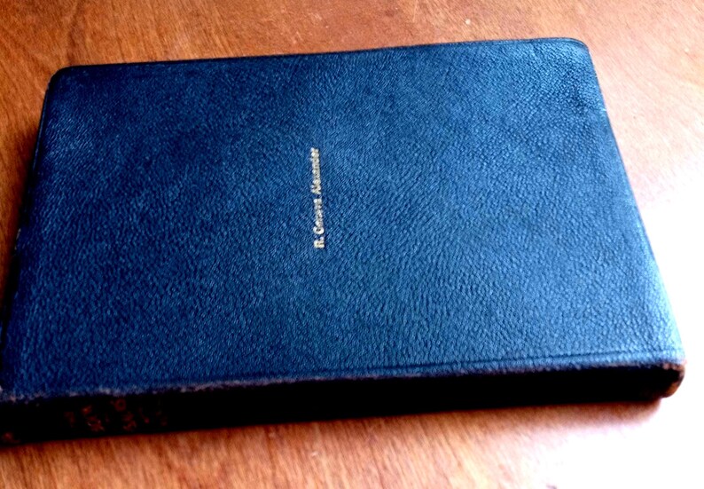 May include: A dark blue rectangular book with a textured cover. The name R. Geneva Alexander is embossed in gold lettering on the front center of the cover. The book has a hard binding and a slightly worn edge along the right side of the cover.