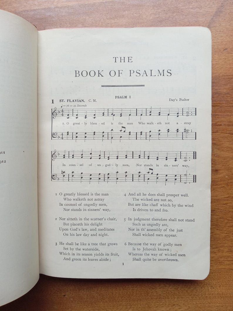 May include: An open book page titled The Book of Psalms, displaying Psalm 1 with musical notation for St. Flavian. The text includes the lyrics O greatly blessed is the man who walketh not astray, printed in black ink on an off-white paper page.