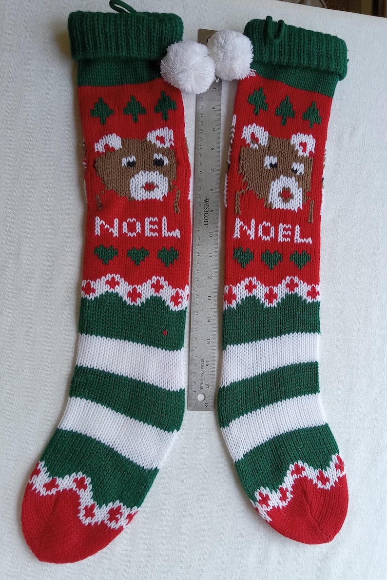 May include: Two red and green Christmas stockings with a reindeer design and the word "NOEL". The stockings have white pom-poms and green and white striped bottoms. The stockings are approximately 18 inches long.