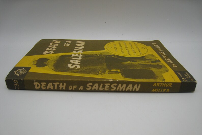 May include: A yellow and brown paperback book titled "Death of a Salesman" by Arthur Miller. The cover features a black and white photo of a man in a suit.