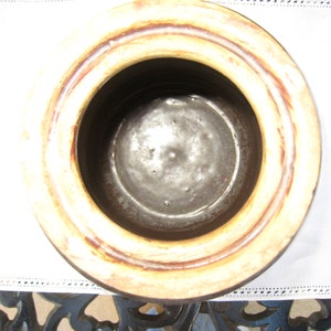 May include: The inside of a brown ceramic crock pot with a cream colored rim. The crock pot has a glazed interior.