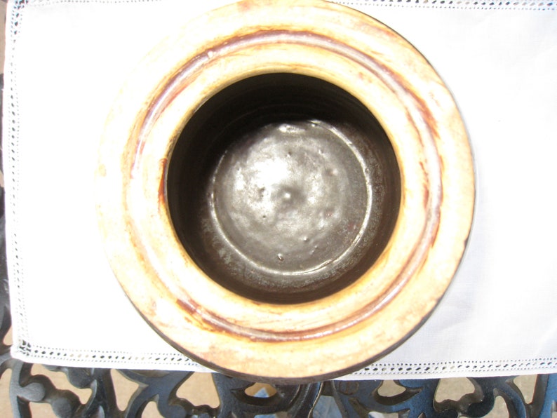 May include: The inside of a brown ceramic crock pot with a cream colored rim. The crock pot has a glazed interior.