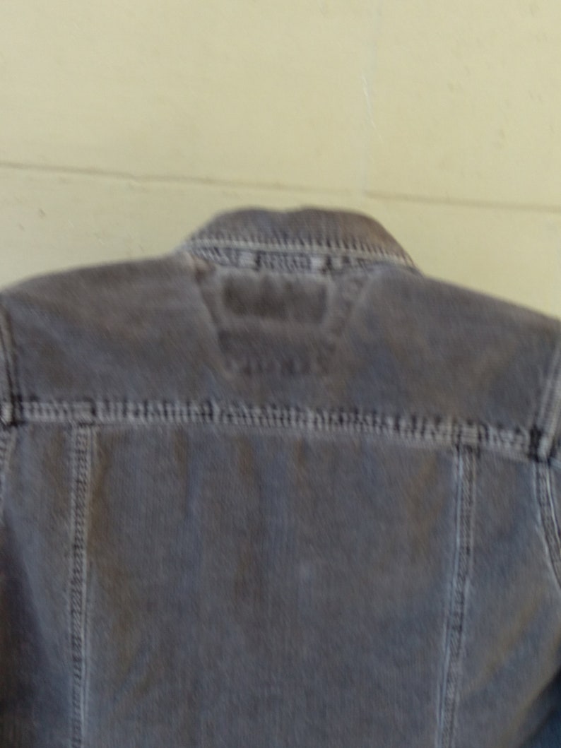 May include: A gray corduroy jacket with a zipper closure and a small label on the back.