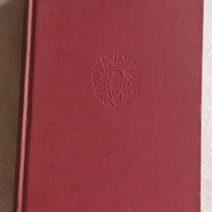 May include: A burgundy hardback book with a decorative embossed design on the front cover.