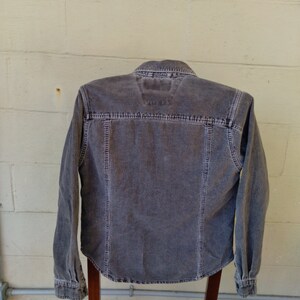 May include: A long-sleeved, dark gray corduroy shirt with a button-up front and a pointed collar.