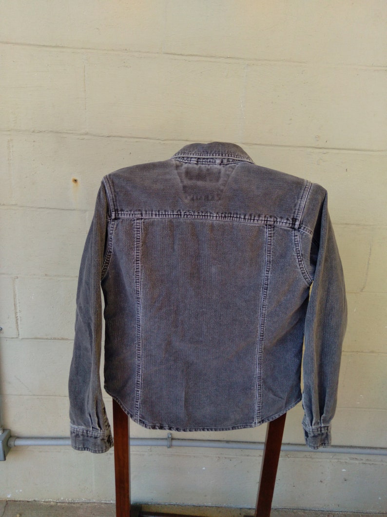 May include: A long-sleeved, dark gray corduroy shirt with a button-up front and a pointed collar.