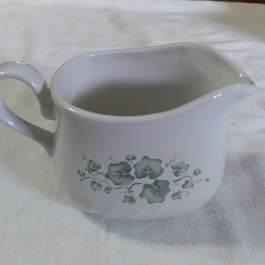 May include: White ceramic creamer with a green vine and leaf design.