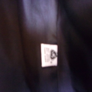 May include: A white tag with black text and a black symbol. The text on the tag reads "The Woolmark Company".