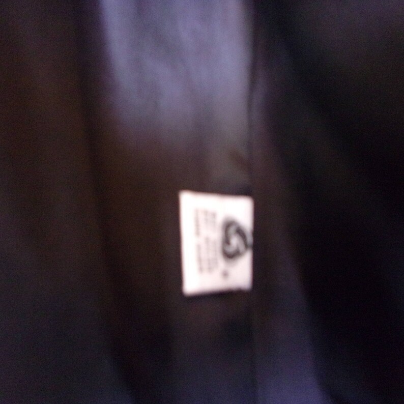 May include: A white tag with black text and a black symbol. The text on the tag reads "The Woolmark Company".