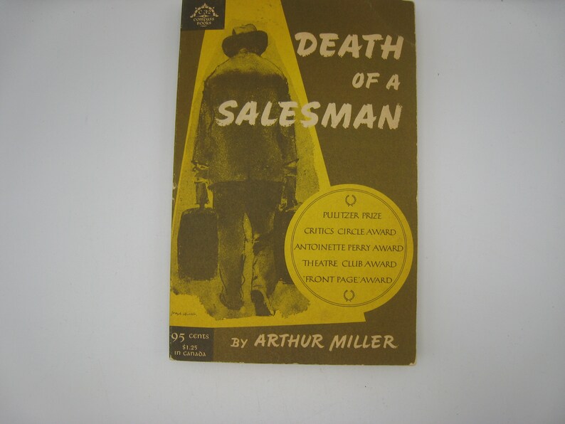 May include: A yellow and brown book cover with the title "Death of a Salesman" by Arthur Miller. The cover features a black and white illustration of a man walking away from the viewer, carrying a suitcase.