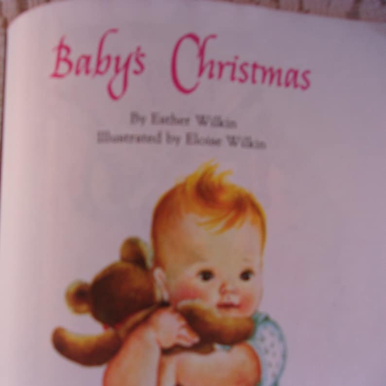 May include: A vintage illustration from the book "Baby's Christmas" by Esther Wilkin. The image features a baby with fair skin and red hair holding a brown teddy bear. The title is in pink script.