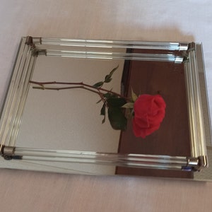 May include: A rectangular mirrored tray with a clear glass frame. A single red rose is reflected in the mirror.