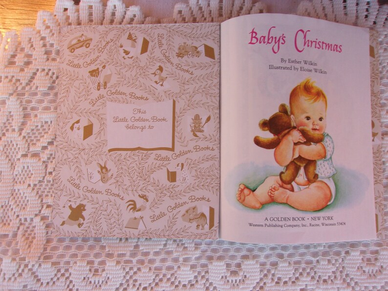 May include: Open vintage book titled "Baby's Christmas" by Esther Wilkin, illustrated by Eloise Wilkin. The cover features a baby holding a teddy bear. The inside cover has a decorative pattern and a space to write the owner's name.