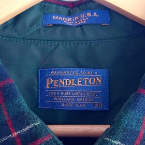 May include: A green plaid wool shirt with a blue interior label reading Warranted To Be A Pendleton 100% Pure Virgin Wool Portland Oregon Since 1863 XL and a secondary blue label stating Made In U.S.A. Dry Clean RN 29685, featuring a button closure.