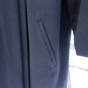 May include: A black wool coat with a single pocket on the front.