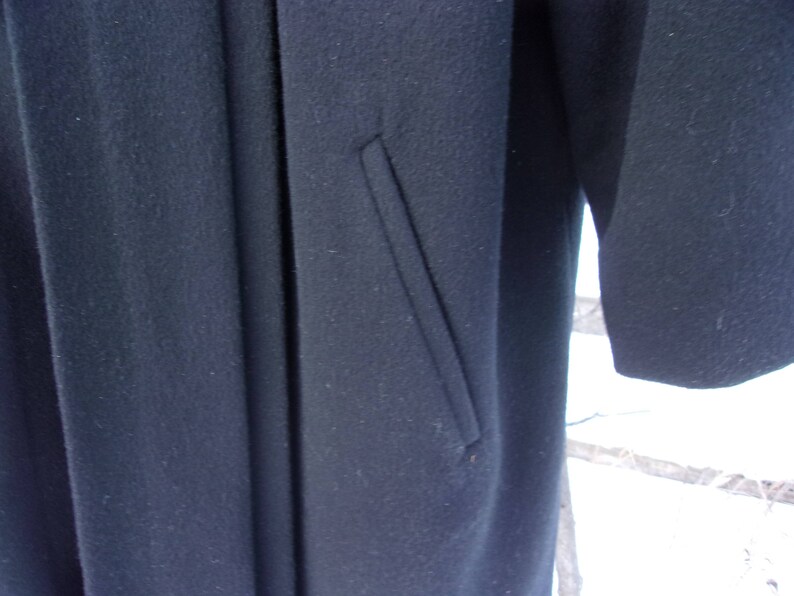 May include: A black wool coat with a single pocket on the front.