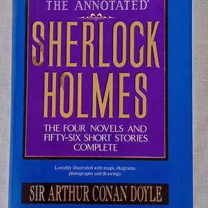 May include: A blue and purple book cover with the title "The Annotated Sherlock Holmes: The Four Novels and Fifty-Six Short Stories Complete" by Sir Arthur Conan Doyle. The book is lavishly illustrated with maps, diagrams, photographs, and drawings.