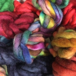 Könnte beinhalten: Nahaufnahme einer Vielzahl von bunten Garnen, darunter Farbtöne von Rot, Orange, Gelb, Grün, Blau und Lila. Das Garn ist in einem lockeren Haufen angeordnet, wobei sich einige Fäden überlappen.