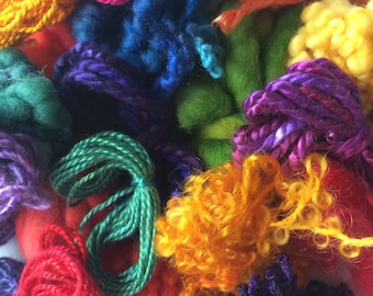 Può includere: Primo piano di una collezione di filati colorati in varie tonalità di rosa, arancione, giallo, verde, blu e viola. Il filato ha diverse trame, tra cui ritorto, ad anello e soffice. L'immagine è ben illuminata, mostrando i colori e le trame vivaci del filato.