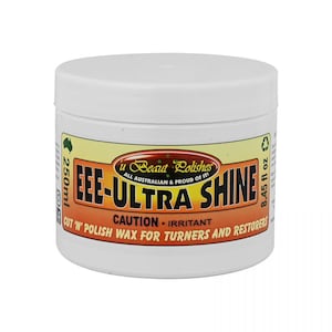 Op de afbeelding: Een witte pot met een geel en oranje etiket waarop staat "u Beaut Polishes ALL AUSTRALIAN & PROUD OF IT! FEE-ULTRA SHINE CUT 'N' POLISH WAX FOR TURNERS AND RESTORERS CAUTION-IRRITANT". De pot bevat 250 ml (8.45 fl oz) polish.