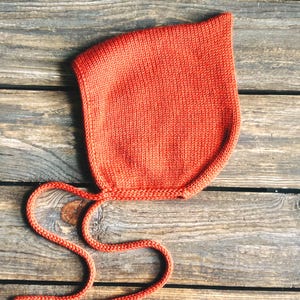 Orange pointy bonnet for baby, hand knitted with soft pure merino wool
