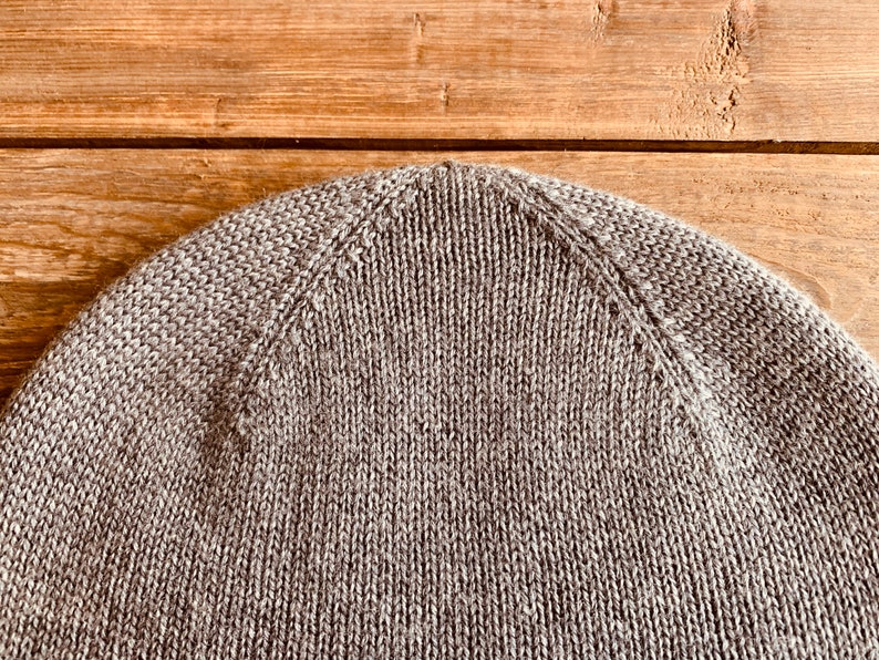 May include: Close-up of the top of a brown knitted beanie hat.