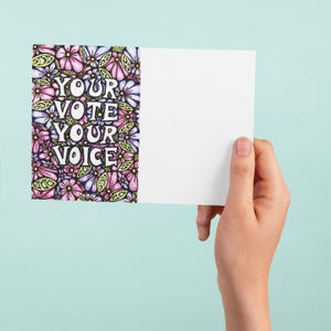 May include: A card with a floral design and the text "YOUR VOTE YOUR VOICE" in white letters on a purple background.