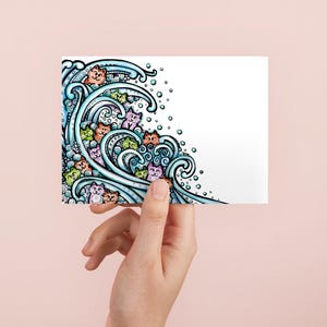 May include: A rectangular greeting card featuring a colorful illustration of stylized blue ocean waves crashing. Within the swirling water patterns are numerous small, cartoon-like cat faces in various shades of orange, green, pink, and purple.