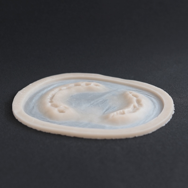Zombie bite silicone prosthetic in vanilla shade on a black surface at a steep angle