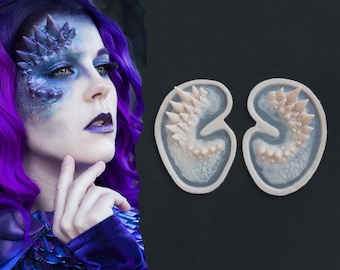 May include: Two silicone molds for creating prosthetic appliances, each featuring a curved, kidney-shaped design with a textured surface of raised, pointed spikes and scales. The molds are light beige in color with a smooth, raised border edge.
