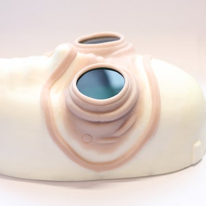 Steampunk silicone prosthetics googles in vanilla shade with green lenses on a white surface