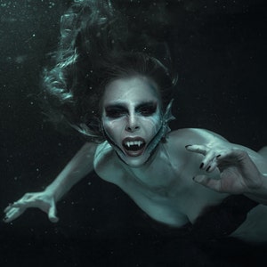 Dark underwater mermaid wearing Mermaid gills prosthetics along her jaw