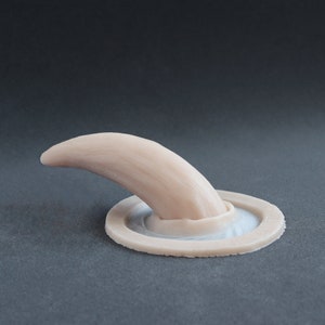 Oni horn silicone prosthetic in vanilla shade on a black surface at a steep angle