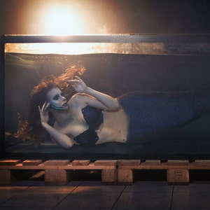 Mermaid wearing mermaid gills along her jaw in a tank of water