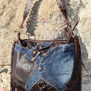 Pu&ograve; includere: Una borsa a mano in pelle marrone con bordi a frangia e un design patchwork in denim. La borsa ha una tracolla lunga e regolabile con tagli decorativi.