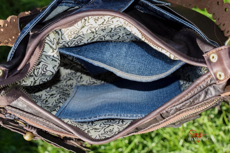 Pu&ograve; includere: L'interno di una borsa in pelle marrone con fodera in denim. La borsa ha una chiusura a zip e una fodera in tessuto fantasia.