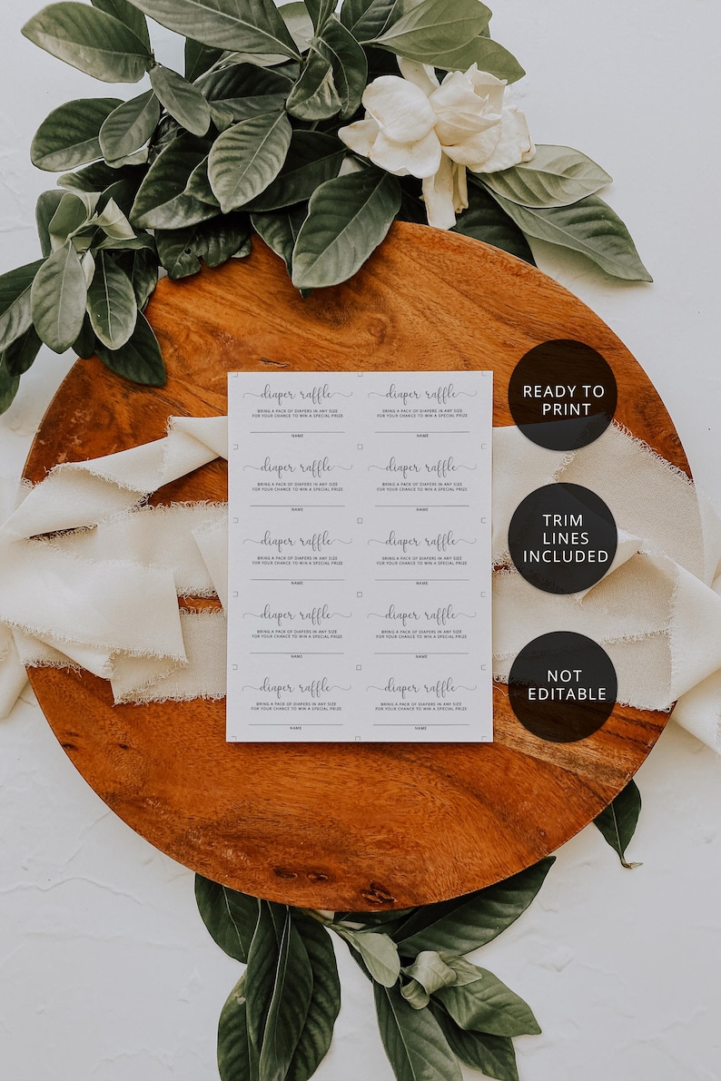 May include: A set of diaper raffle cards with the text "diaper raffle" in elegant script. The cards are on a wooden surface, surrounded by greenery and white flowers. The text "READY TO PRINT", "TRIM LINES INCLUDED", and "NOT EDITABLE" are also visible.