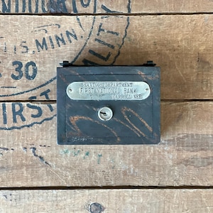 May include: A small wooden box with a metal lock and a silver plaque that reads "Savings Department First National Bank Carroll, Neb. 5".