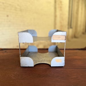 May include: A two-tier metal file organizer with a light gray finish. The organizer has a label on the top tier that reads "Extra Copies".
