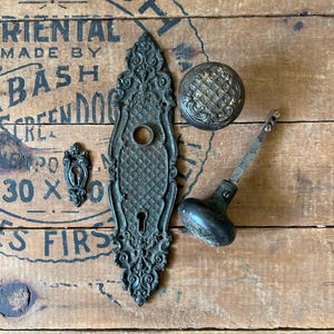 May include: Antique door hardware set in black with ornate details. The set includes a door knob, a door plate, and a keyhole cover.