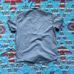 以下が含まれることがあります： 薄い青色のボタンダウンの半袖シャツ。尖った襟が特徴です。